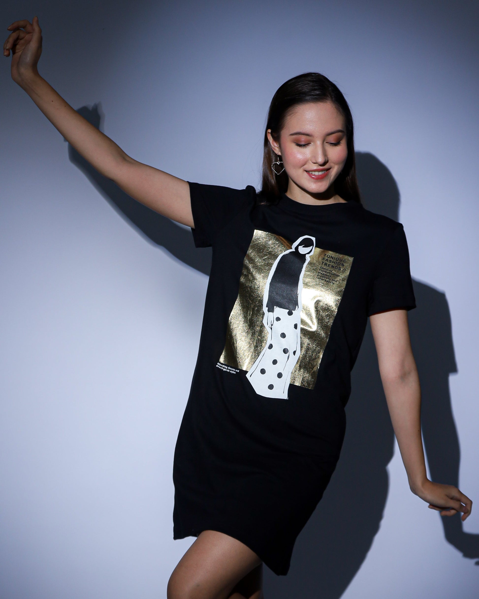 Woman wearing a black gold foil prited t-shirt dress with a graphic design